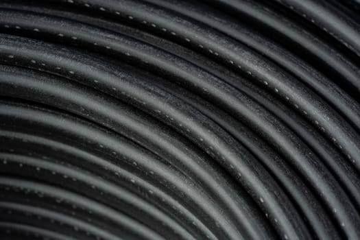 A close-up photo of a coil of black electrical wire with blue and white wires running along the outer edge.