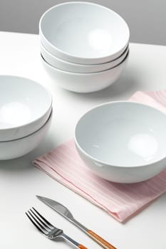 Stylish table setting with white dishware on white tablecloth close up