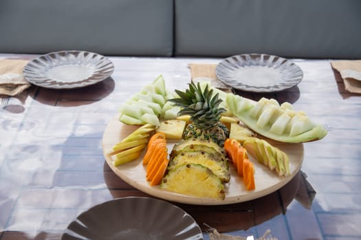 variety of Fresh fruits, cut on a large dish on the table, pieces of pineapple, orange, melon and pear,buffet menu on the table, vitamins all year round