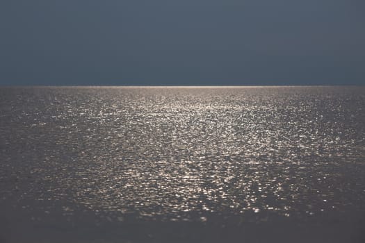 Sun glare on the sea surface in calm, breezy weather. Natural background and texture.