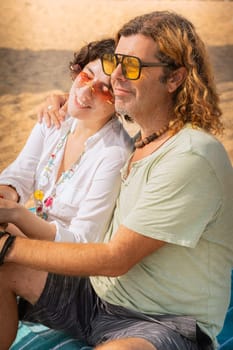 Smiling couple wearing sunglasses enjoying a vacation embracing looking at the sea.