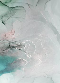 An abstract art photograph featuring flowing ink swirls in shades of teal, silver, and black. The image captures the beauty of fluid movement and organic forms.