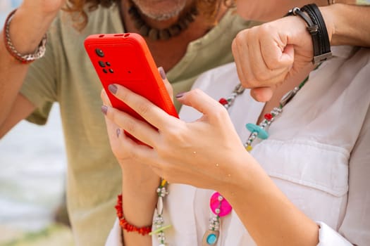 Middle aged man and woman sitting on the beach smiling browsing smartphone apps. Concept:Vacation and Technology