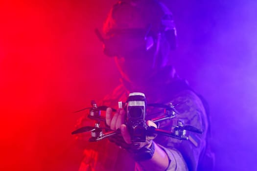 Soldier in gear holds drone against a red and blue smoky background, conveying intensity and military action