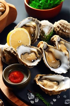 Fresh oysters with lemon and sauce on a table with ingredients. Wallpaper. Vertical photo for national oyster day promotions.