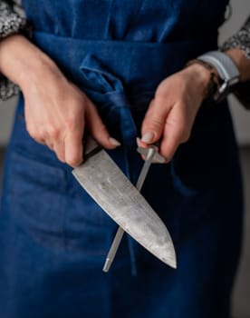 Big Kitchen Knife And Sharpener In Female Hands Are In Close-Up View