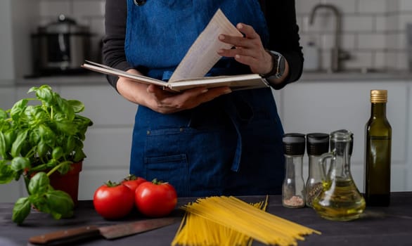 Woman Reads Recipe Near Table With Pasta, Tomatoes, Spices, And Basil