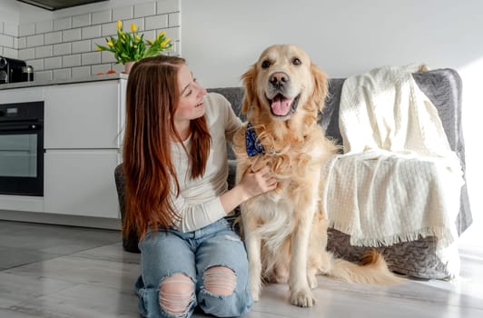 Teenage Girl With Golden Retriever Dog At Home In Kitchen