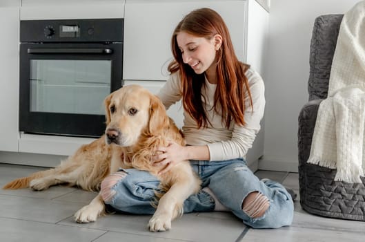 Teenage Girl With Golden Retriever Dog At Home In Kitchen