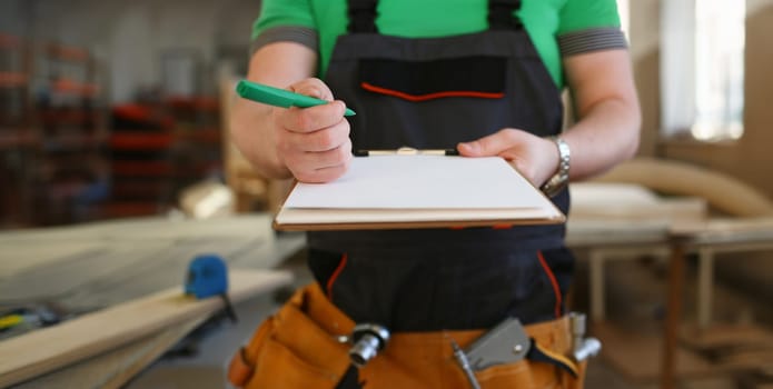 Arms of worker offer clipboard with green pen closeup. Manual job DIY inspiration improvement fix shop graphic joinery startup workplace idea designer career wooden bar ruler