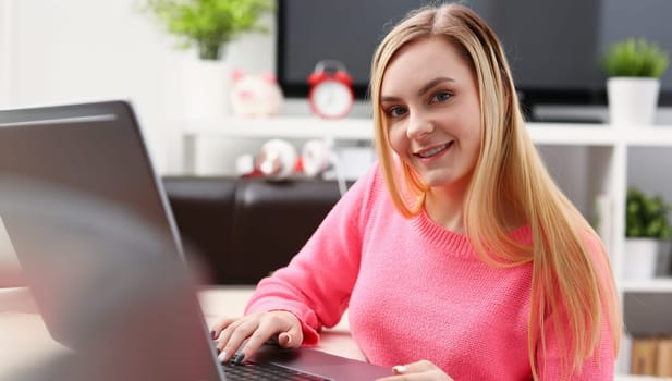 young beautiful blond woman sit in livingroom work on laptop pleasant weekends concept