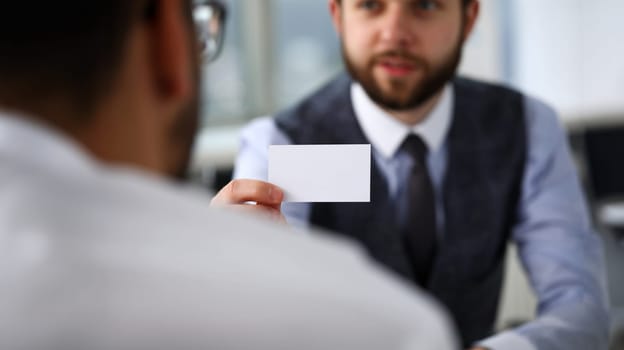 Male arm in suit give blank calling card to visitor closeup. White collar colleagues company name exchange job interview sale clerk id executive or ceo finance support formal identity etiquette