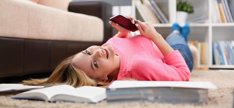 young beautiful woman have a rest lie on the floor hold smartphone in arms nice holiday concept