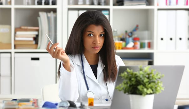 Beautiful black smiling female doctor sit at workplace. Physical and disease prevention patient aid exam visit 911 ward round prescribe remedy healthy lifestyle consultant profession concept