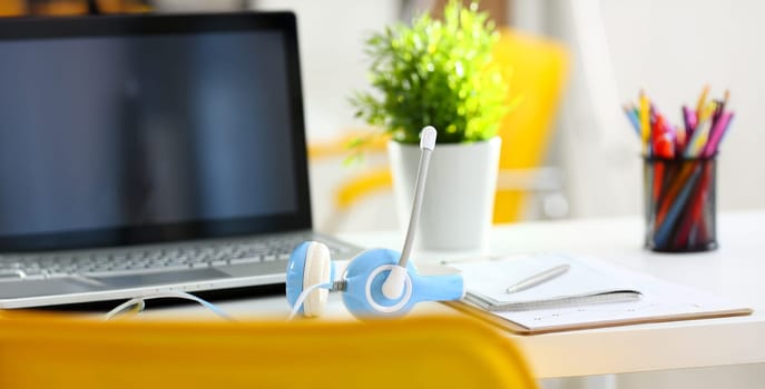 Empty remote office workplace with laptop pc and headset closeup. Receptionist or secretary of contact data center desktop keyboard device desk table ip telephony or callcenter voice message system