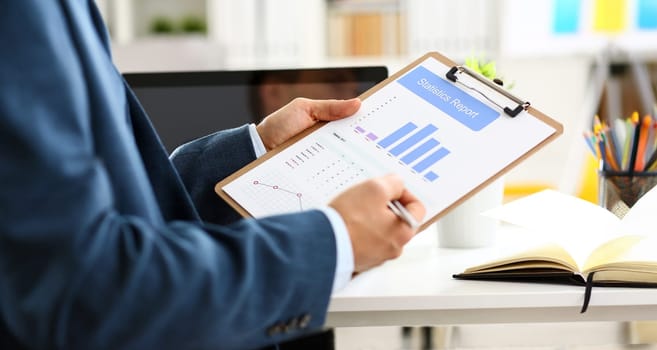 Male arm in suit show stats graphic clipped to pad in office closeup. Stock exchange market advisor participation in negotiation study trade process white collar inspector check or explain money data