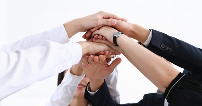 Group of people in suits crossed hands in pile for win closeup. White collar leadership high five cooperation initiative achievement corporate life style friendship deal heap stack concept