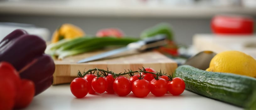 Cherry tomatoes lie on a cutting board in kitchen against backdrop of greenery healthy eating concept
