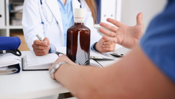 Alcoholic hold in arm empty bottle at doctor reception office closeup. Grief and despair of intoxicated for sober life change drunkenness bad habit lifestyle dependence and temperance concept