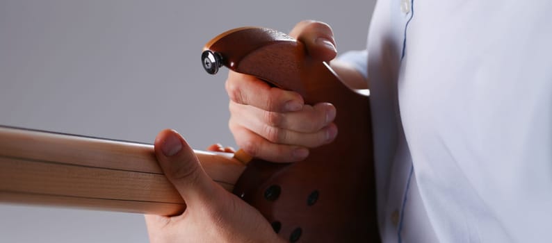 Male arms holding and playing classic shape wooden electric guitar closeup. Six stringed learning musical school education art leisure electrical vintage stage shop having fun enjoying hobby concept