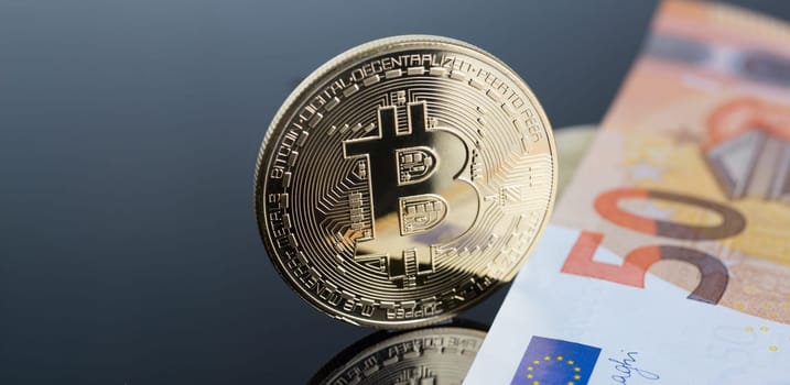 The coin of crypto currency bitcoin against background euro banknote subject gold exchange pyramid for money in connection with the growth or fall exchange rate closeup.