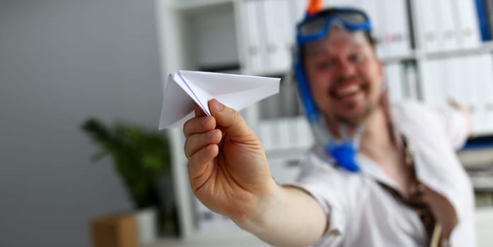 Man wearing suit and tie in goggles and snorkel play with fly paper plane in office closeup. Count days to leave annual day off workaholic freedom fun tourism resort idea ticket sale overseas concept
