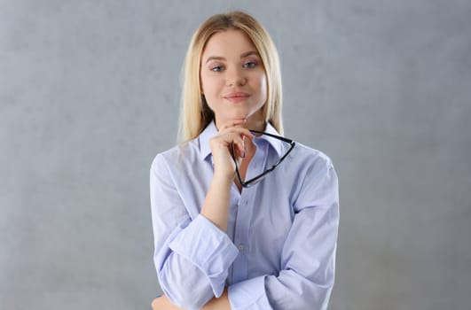 Portrait of a sexy woman in a man's shirt wearing glasses on a gray background looks at the camera and smiling look advice to give wants objections are not accepted.