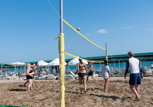 two teams of vacationers play beach volleyball at sea on vacation, the ball flies through the net against a clear blue sky, ball matches and active activities, Belek, Turkey, May 31, 2024