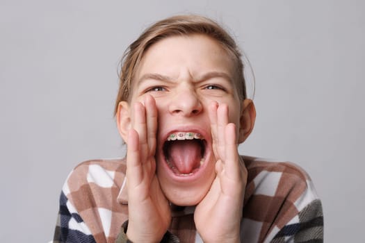 close-up portrait of a teenager with braces, the boy screams attracting attention, tell me urgently