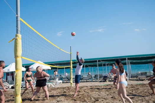 two teams of vacationers play beach volleyball at sea on vacation, the ball flies through the net against a clear blue sky, ball matches and active activities, Belek, Turkey, May 31, 2024