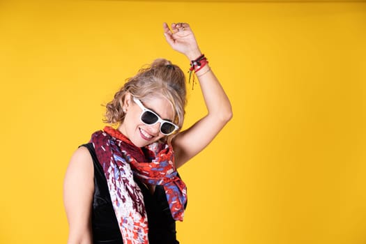 A woman is wearing sunglasses and a scarf, protecting her eyes and neck from the sun while looking stylish.