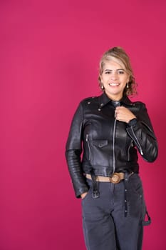 A woman in a black leather jacket striking a pose for a picture with a confident stance and expression.