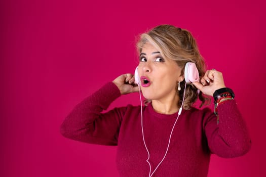 A woman wearing headphones and a red shirt. She is looking at the camera with her mouth open