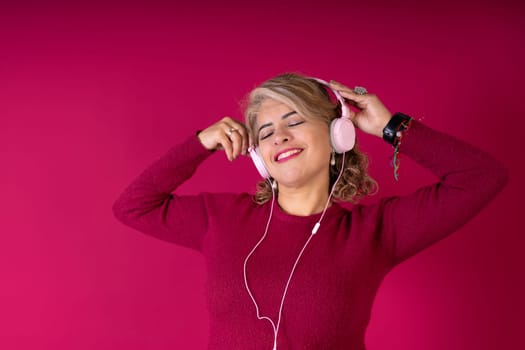 A woman is wearing headphones and smiling while listening to music. Concept of relaxation and enjoyment as the woman immerses herself in the music