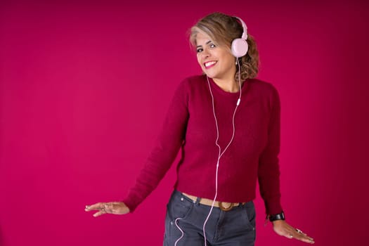 A woman is seen wearing headphones and a red shirt, immersed in listening to music.