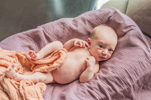 A newborn lies in his cozy cocoon on muslin swaddles. This serene moment captures the comfort and security of a newborn, highlighting the gentle care and nurturing environment.