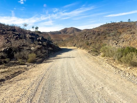 Winding dirt road through rugged terrain in Flinders Ranges under a clear blue sky.