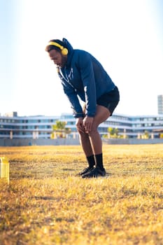 Sporty young man with sports headphones doing stretches outdoors.