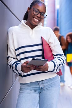 Young smiling student with notebook in hand uses social networks with smartphone applications and wireless technology outdoors.