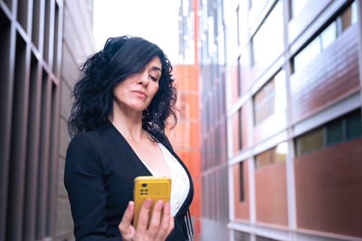 Smiling business woman having a video call with cell phone and smiling outdoors.