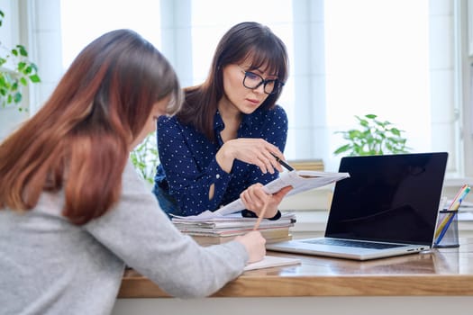 Female teacher mentor teaching young teenage girl student using laptop computer. Education, adolescence, learning, technology, teaching concept