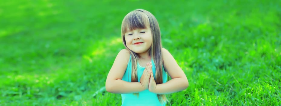 Portrait of happy little girl child standing on the grass in summer green park