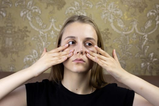 Young girl massages her face with hands for skin care, warming up the facial tissues of girl for beauty procedure