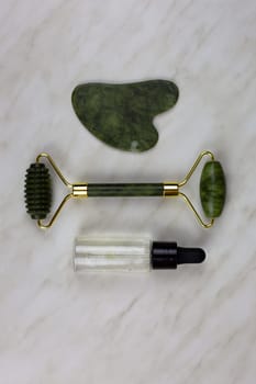 Guasha scrub for caring for body skin lies next to wrinkle smoothing roller and moisturizing oil, facial skin care set lies on white table
