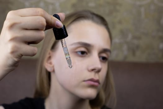 Pipette with oil for facial massage and moisturizing skin against the background of young girl face during skin care procedure