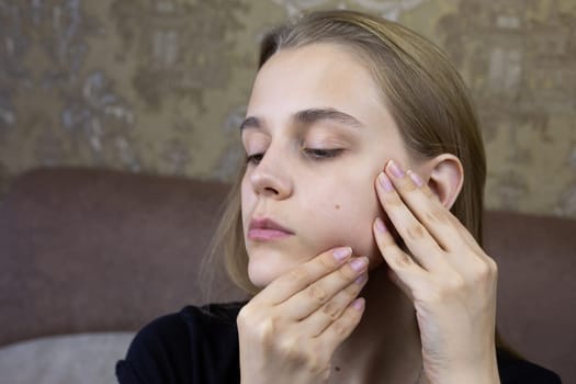European young girl makes facial massage with her hands to herself, special skin care product for the girl face