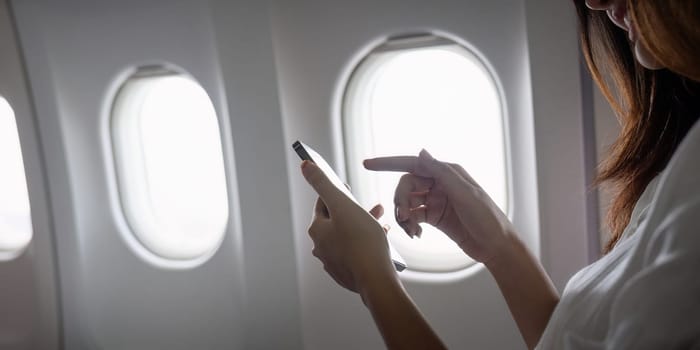 A passenger using a smartphone on an airplane, showcasing modern technology and connectivity during flight travel.