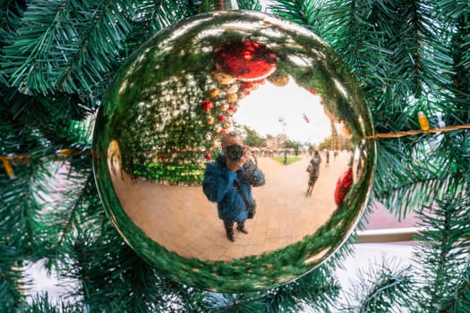 the photographer takes pictures of himself and a beautiful background through a Christmas toy that is on the Christmas tree. photo