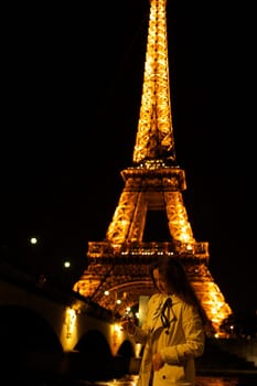 Girl with a glass against the backdrop of the glowing Eiffel Tower in. High quality photo