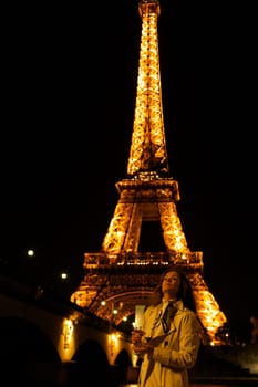 Girl with a glass against the backdrop of the glowing Eiffel Tower in. High quality photo